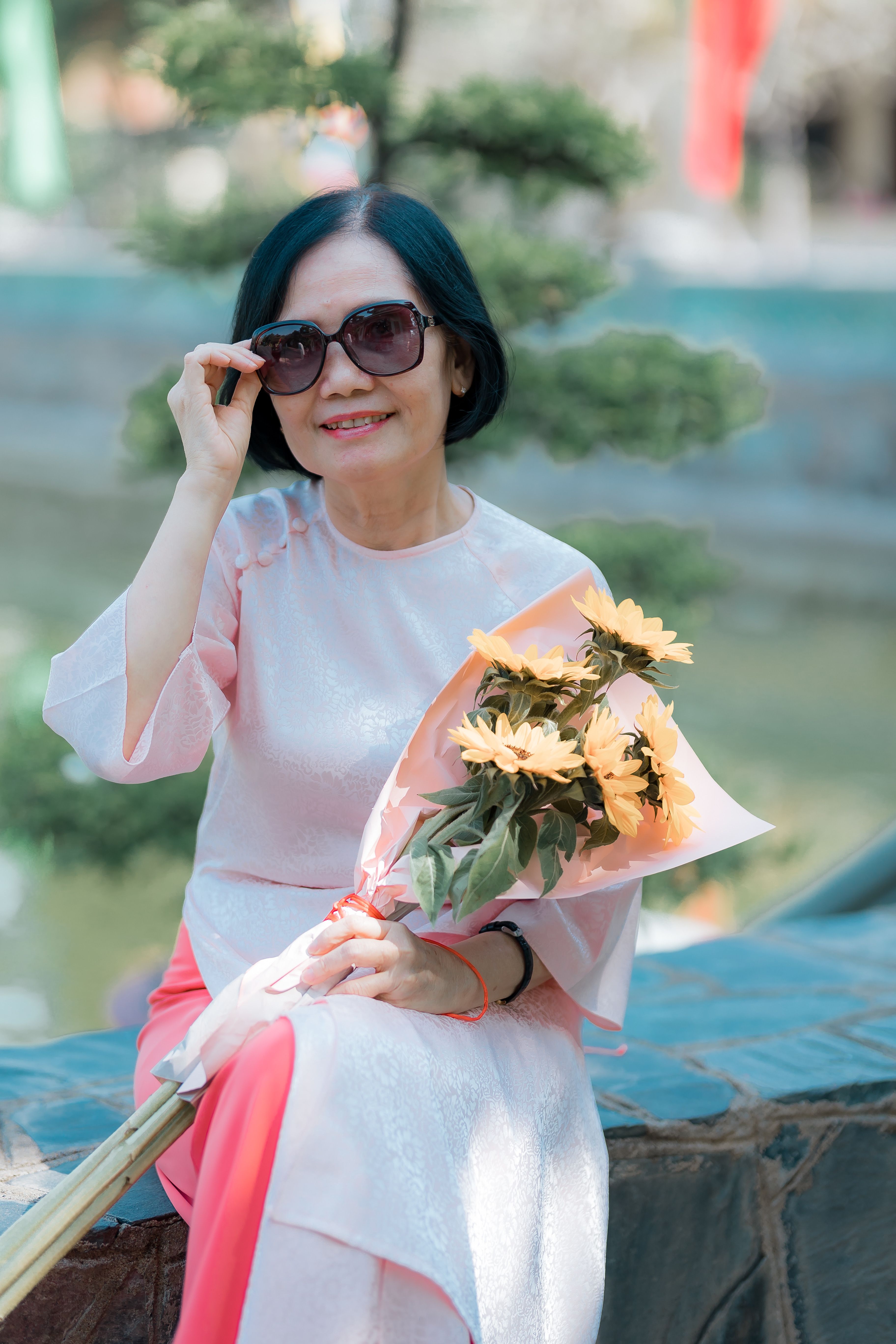 Smiling woman in traditional attire holding flowers · Free Stock Photo