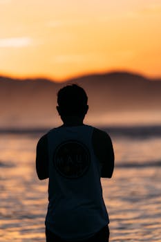 Silhouette of a man enjoying a vibrant sunset on a beach in El Salvador.