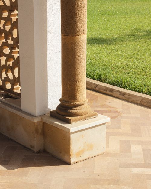 Free Stone pillar next to patio, with a green lawn in sunlight, architectural details visible. Stock Photo