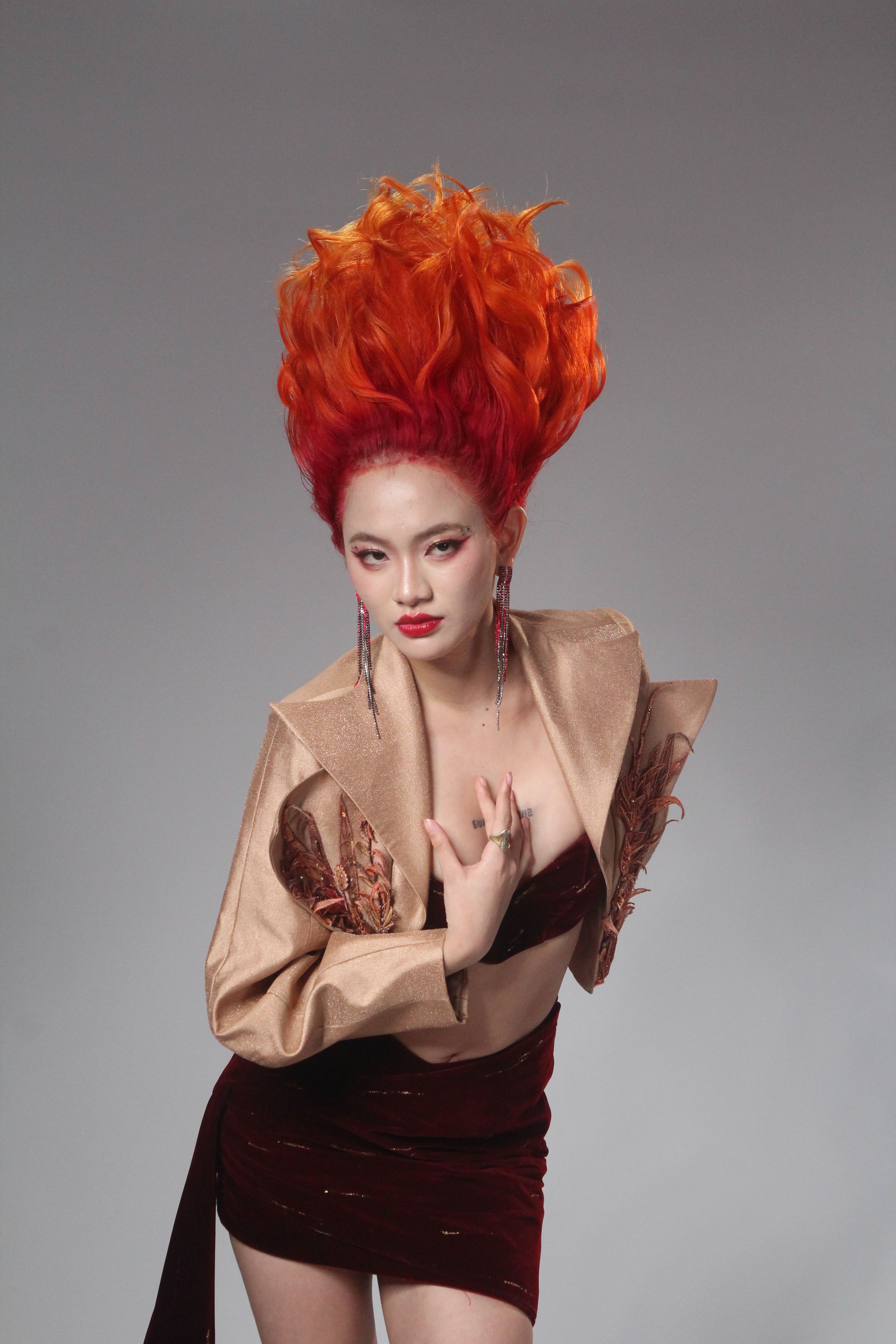 Bold fashion portrait featuring a model with striking orange and red hair against a simple backdrop.