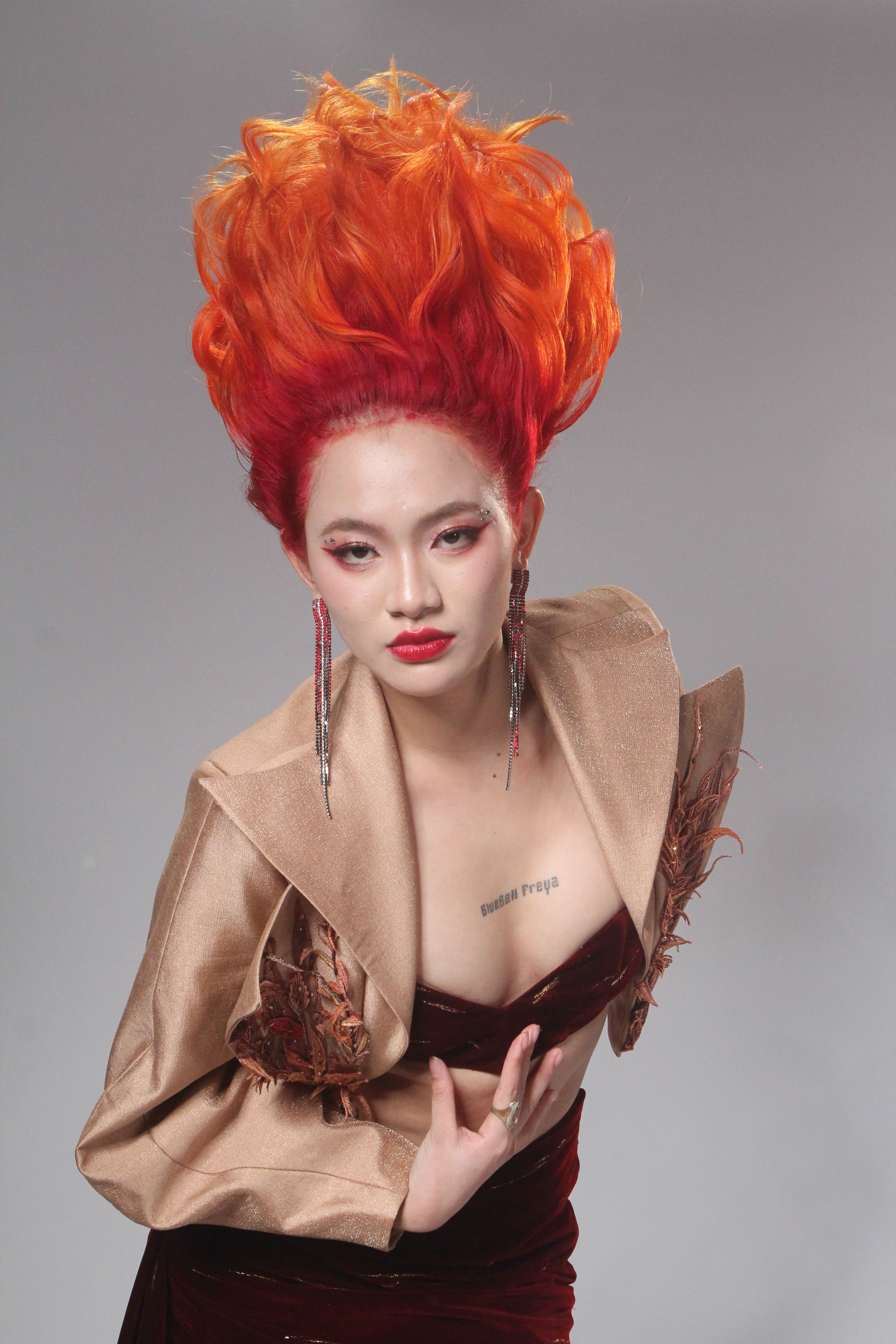 Striking fashion portrait of a model with vibrant orange hair and stylish outfit.