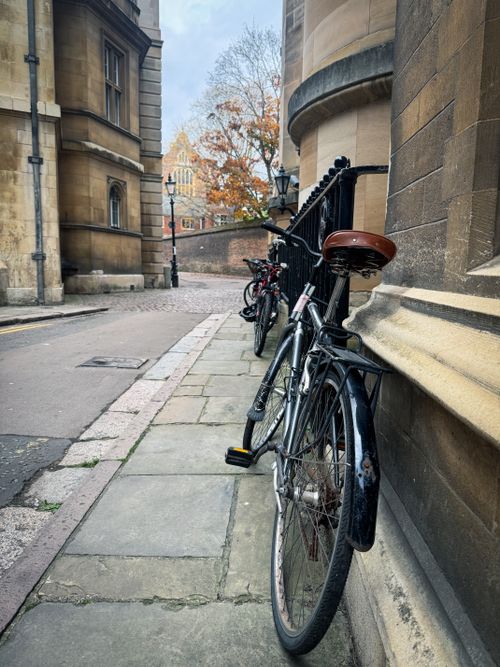 Free Two bicycles parked against a historic building in Cambridge, England, showcasing classic architecture and autumn atmosphere. Stock Photo