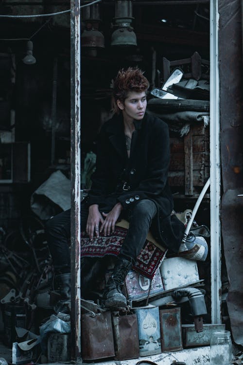 Man Sitting on a Pile of Metal Tins