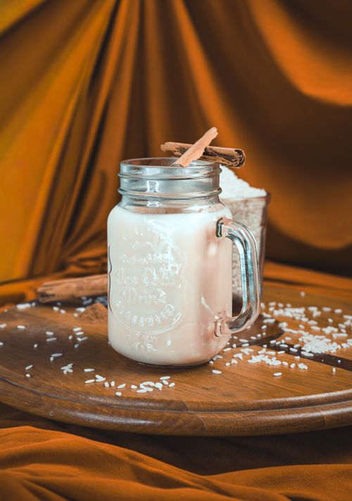 Free Rustic scene of cinnamon horchata in a mason jar with scattered rice and cinnamon sticks. Stock Photo