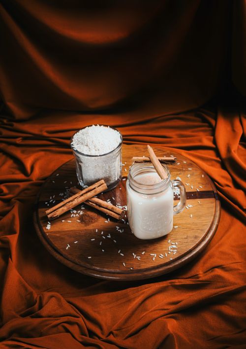 Free A cozy arrangement featuring a cinnamon-infused rice drink on a wooden platter, evoking a warm and comforting atmosphere. Stock Photo