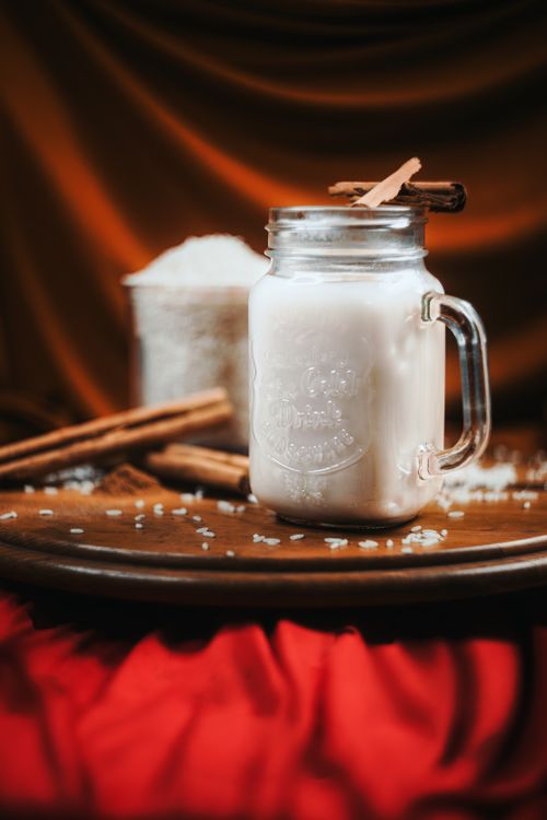 Free Cozy mug of creamy cinnamon rice milk on a wooden table with scattered grains. Stock Photo