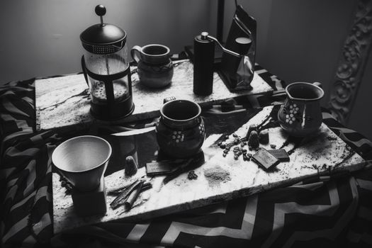 Elegant black and white photo of a coffee setup with French press and rustic mugs on marble.