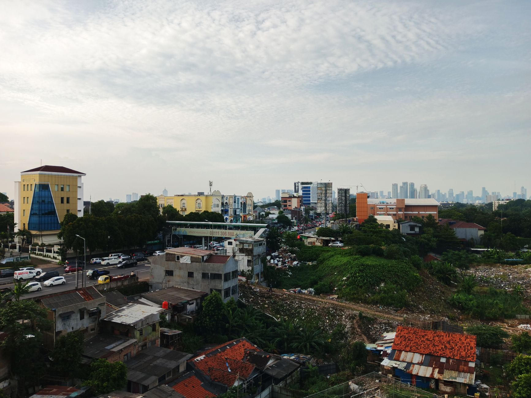 Aerial photo of Jakarta showing a mix of urban development and green areas, highlighting city growth.