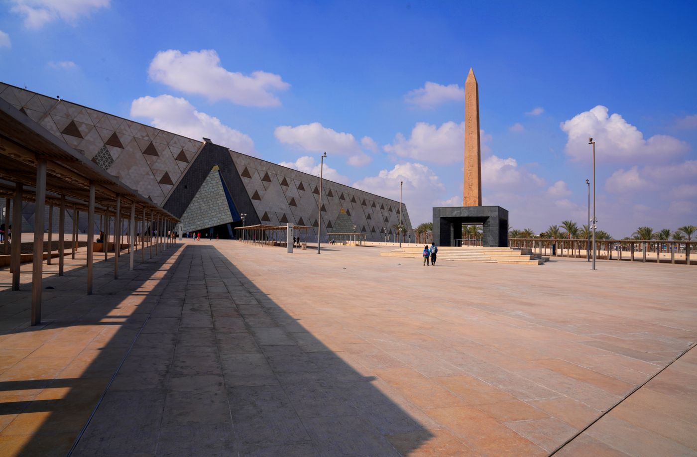 The Grand Egyptian Museum and an obelisk under a blue sky in Giza