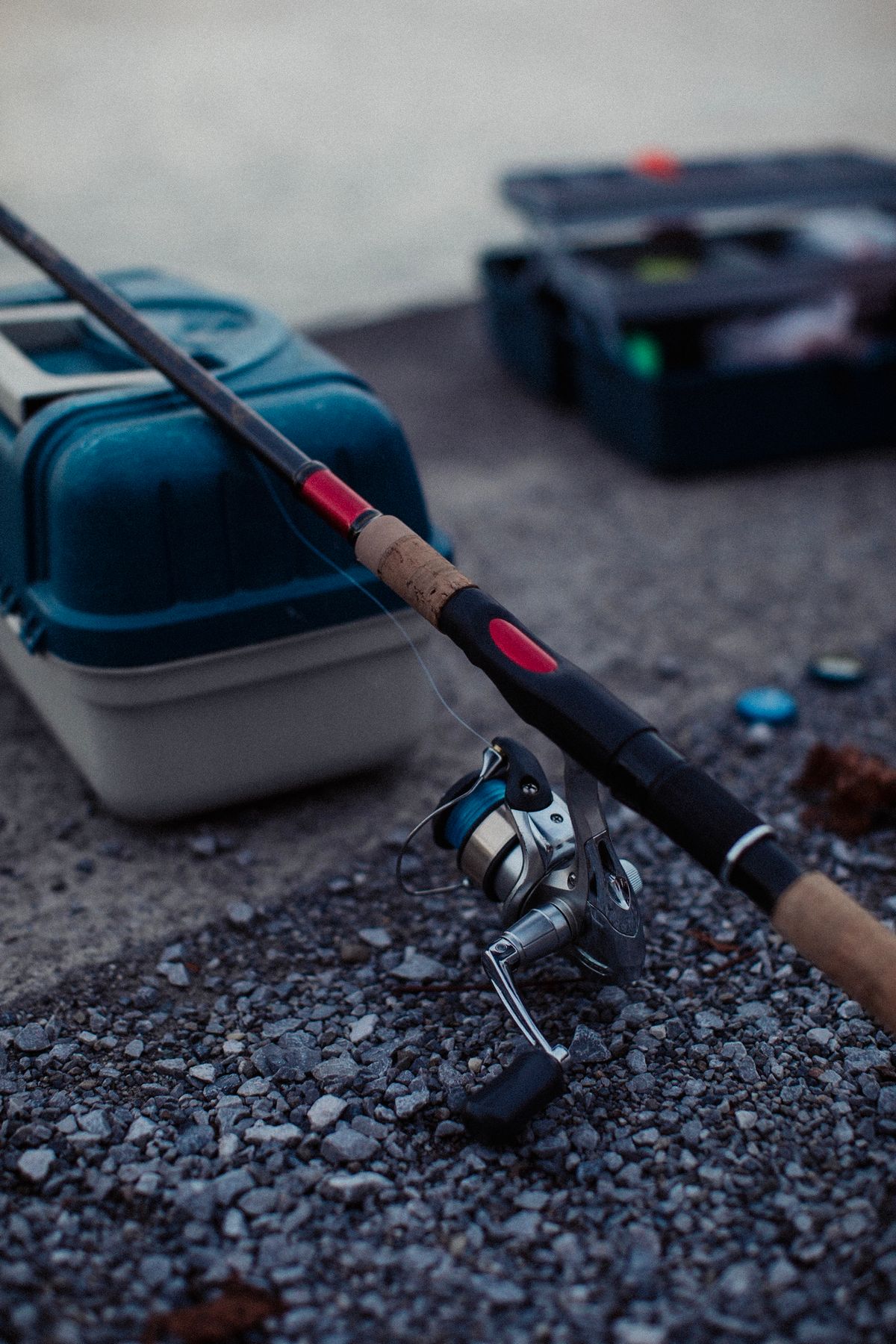A fishing rod and tackle box ready on a gravel bank