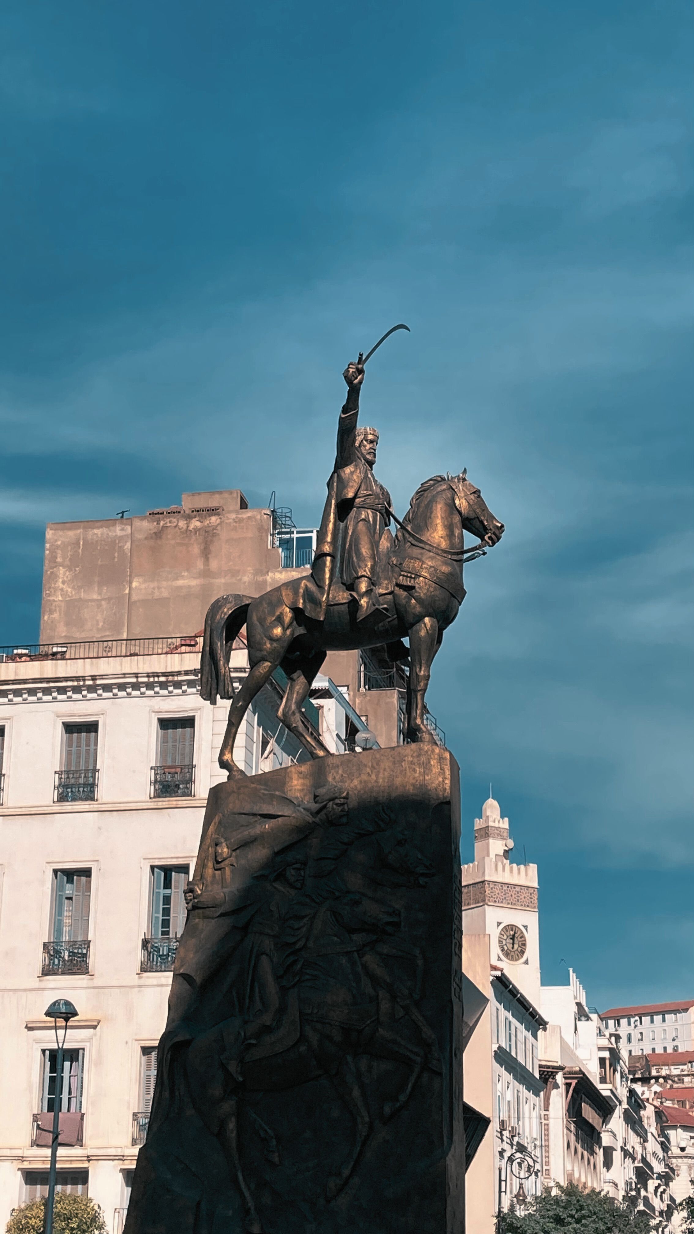 Majestic statue of a rider on horseback with upraised sword in an urban setting.