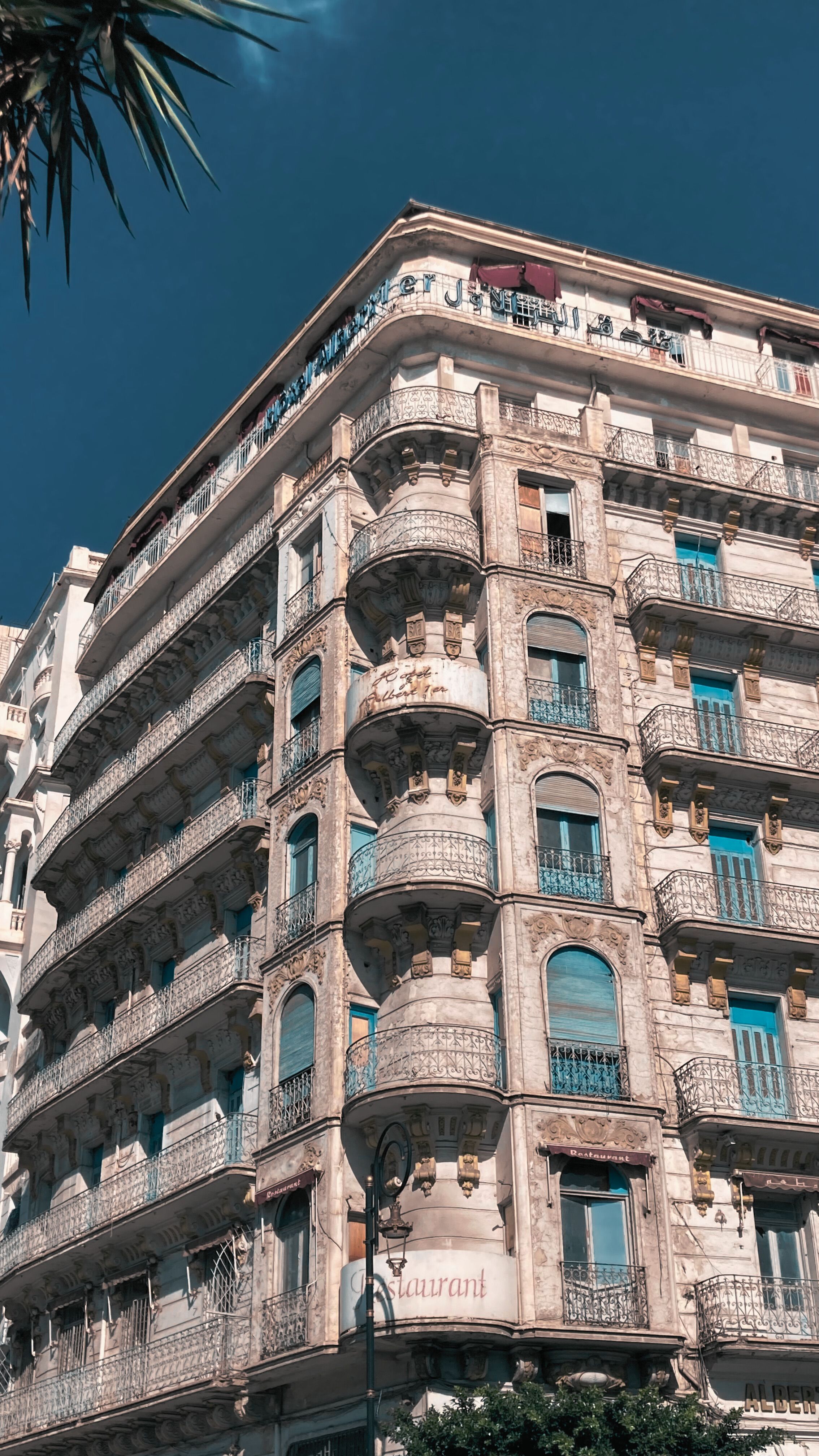Elegant historic building with ornate balconies under bright blue sky.