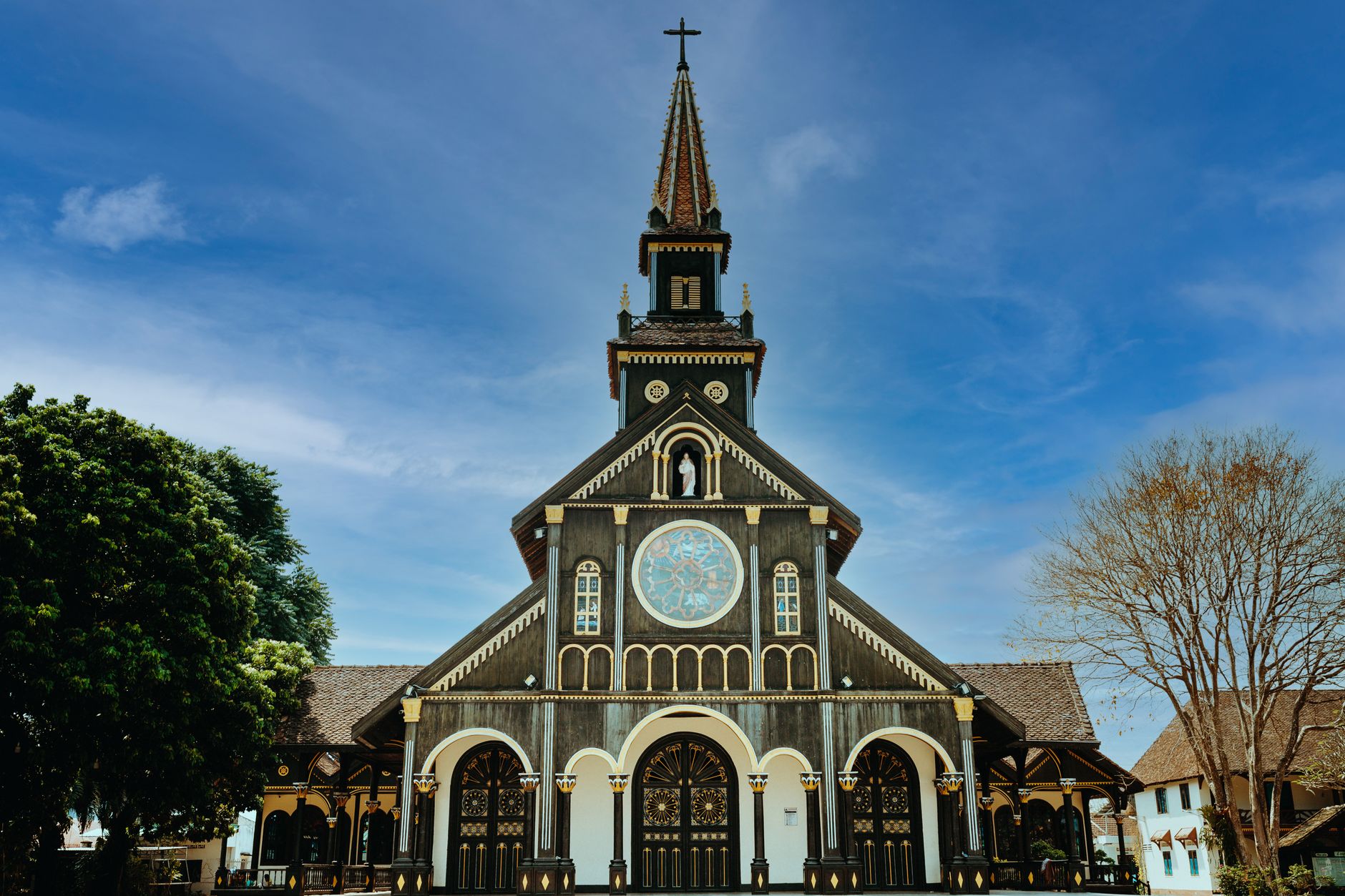 Stunning view of the unique Gothic wooden church in Kon Tum, Vietnam under a clear blue sky.