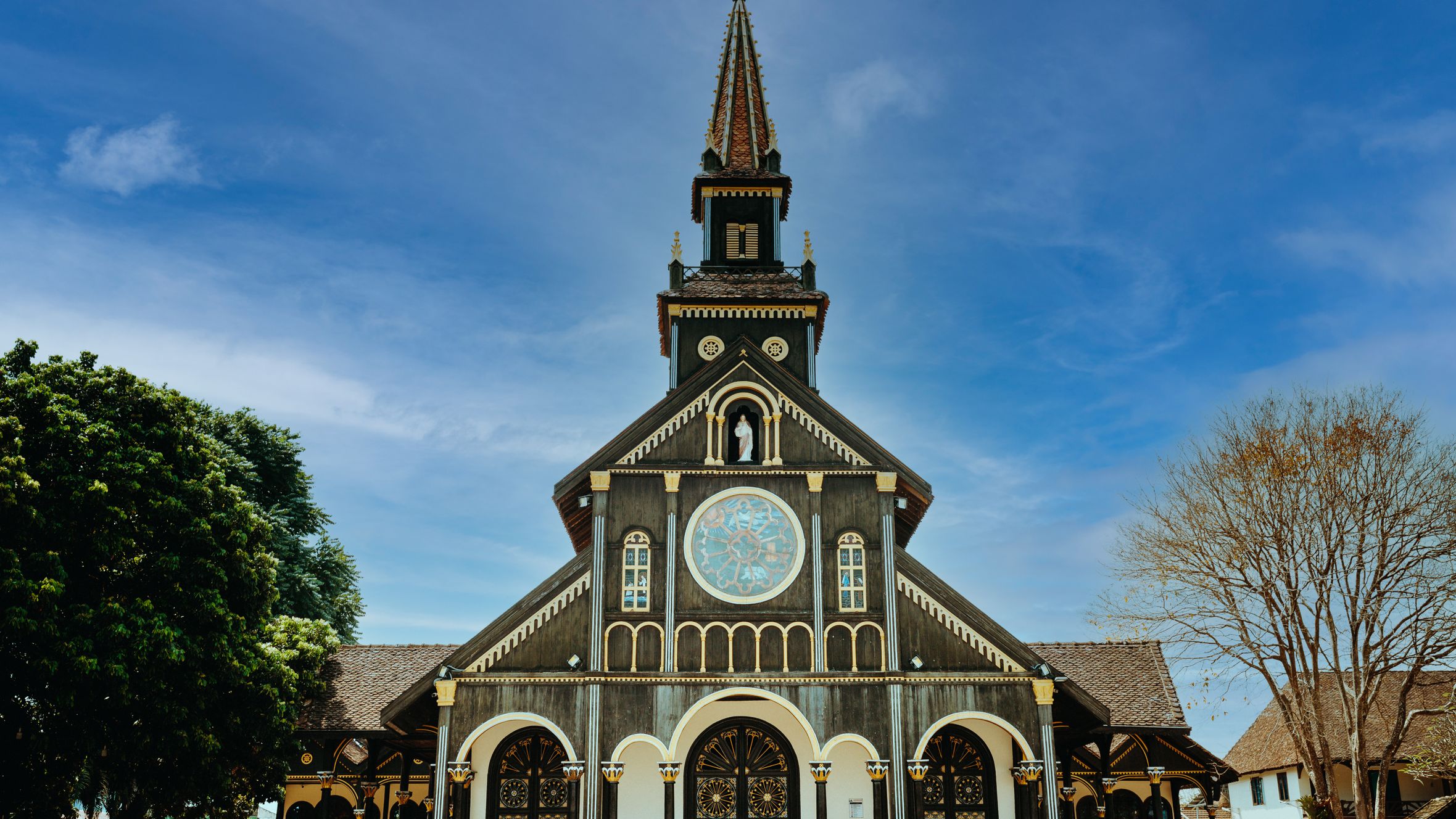 Stunning view of the unique Gothic wooden church in Kon Tum, Vietnam under a clear blue sky.