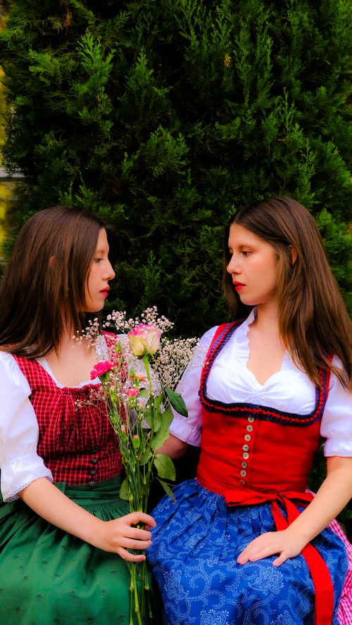 Free Two women in Graz, Austria wearing dirndls and holding flowers, evoking a rustic autumn ambiance. Stock Photo