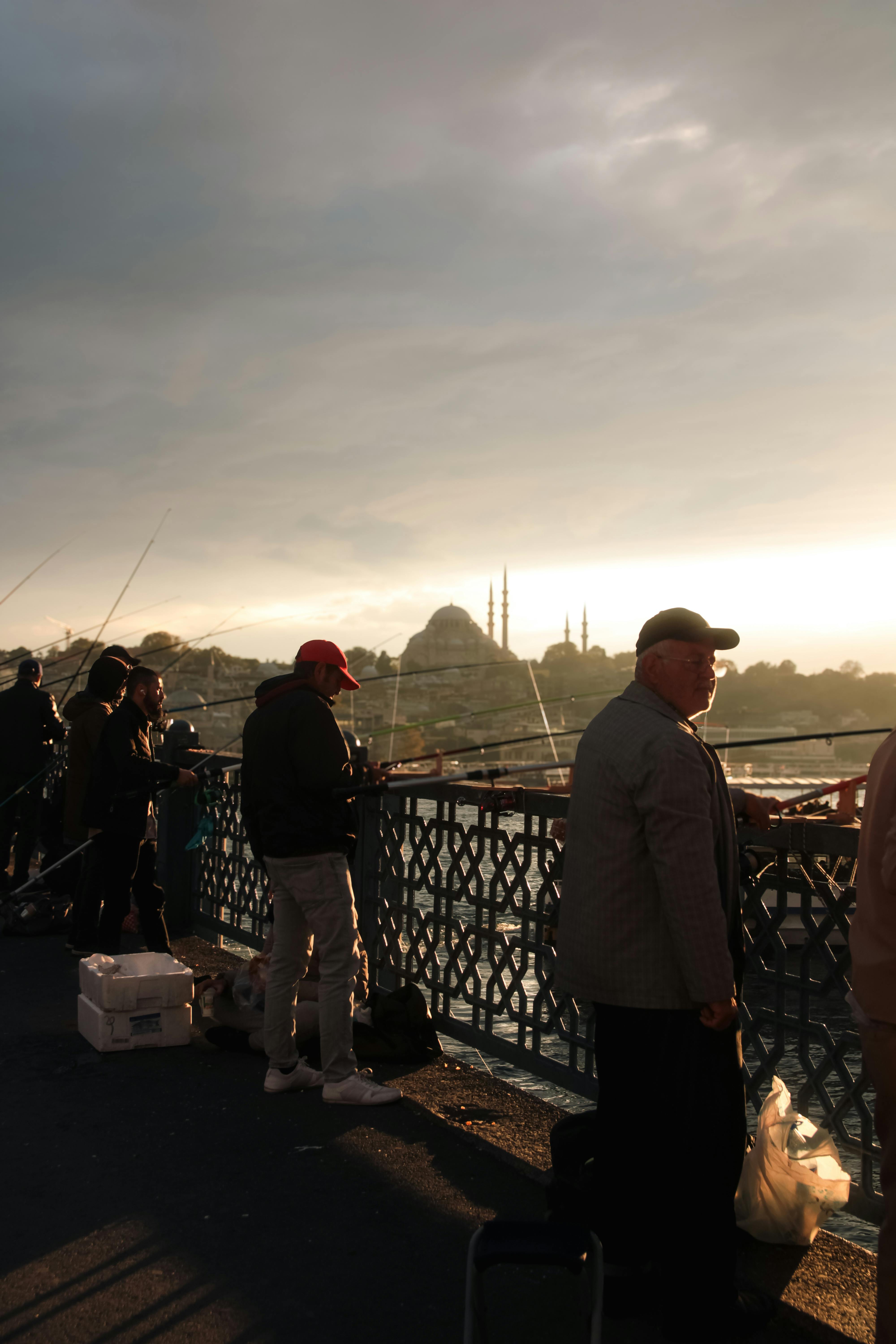 Gratuit Pêcheurs lançant des lignes au coucher du soleil sur le pont de Galata, avec les toits d'Istanbul en arrière-plan. Photos