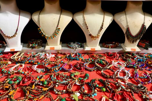 Colorful handmade jewelry showcased on mannequins at an outdoor market.
