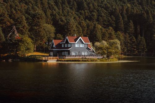 Free Charming house by a tranquil lake surrounded by dense forest at daytime. Stock Photo