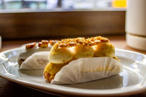 Free Delicious gourmet eclairs topped with cream and nuts on a white plate. Stock Photo