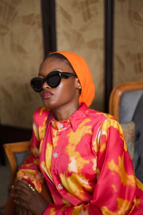 Free Stylish portrait of a woman in vibrant tie-dye attire and sunglasses, exuding confidence. Stock Photo