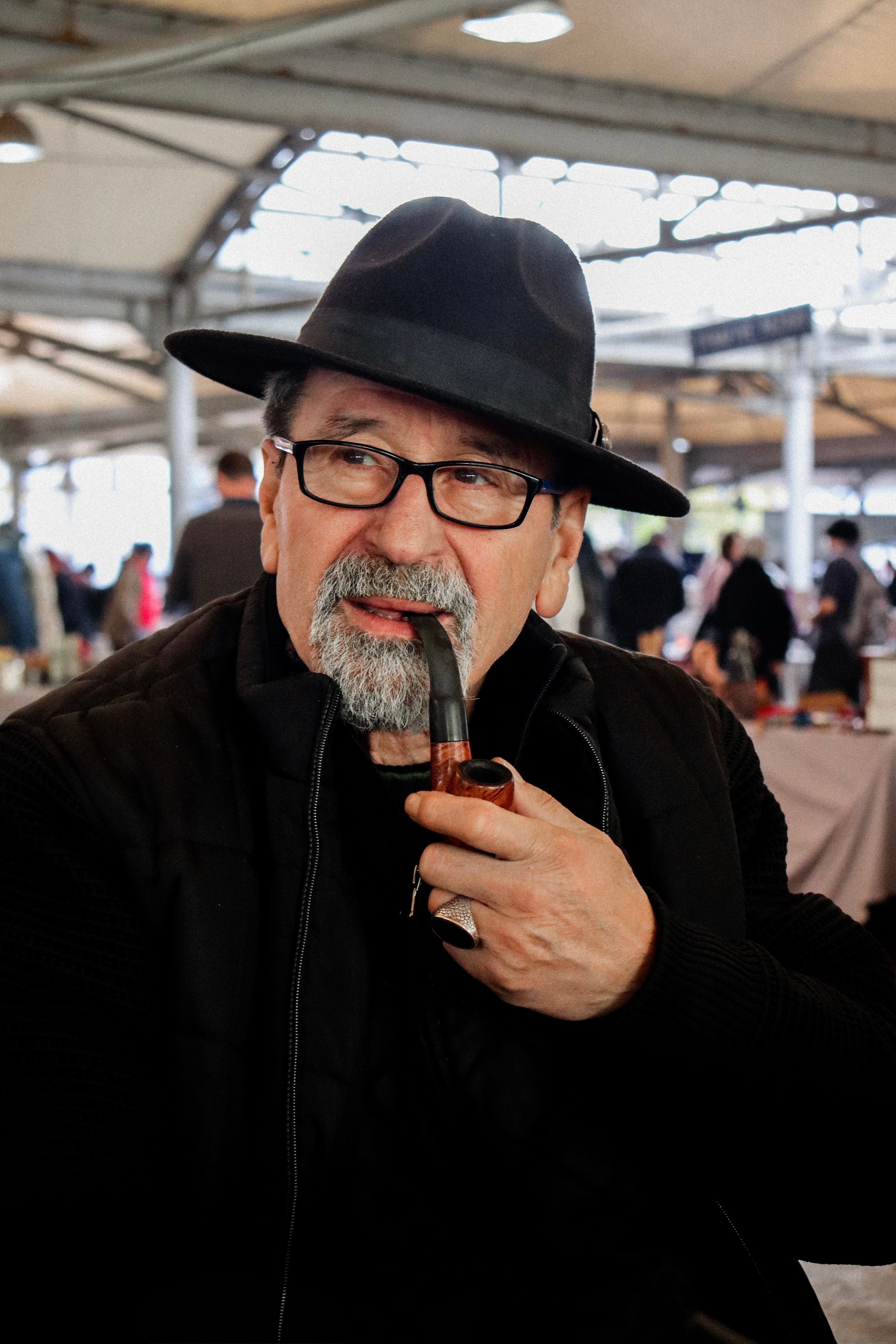 Man wearing hat and smoking pipe indoors · Free Stock Photo