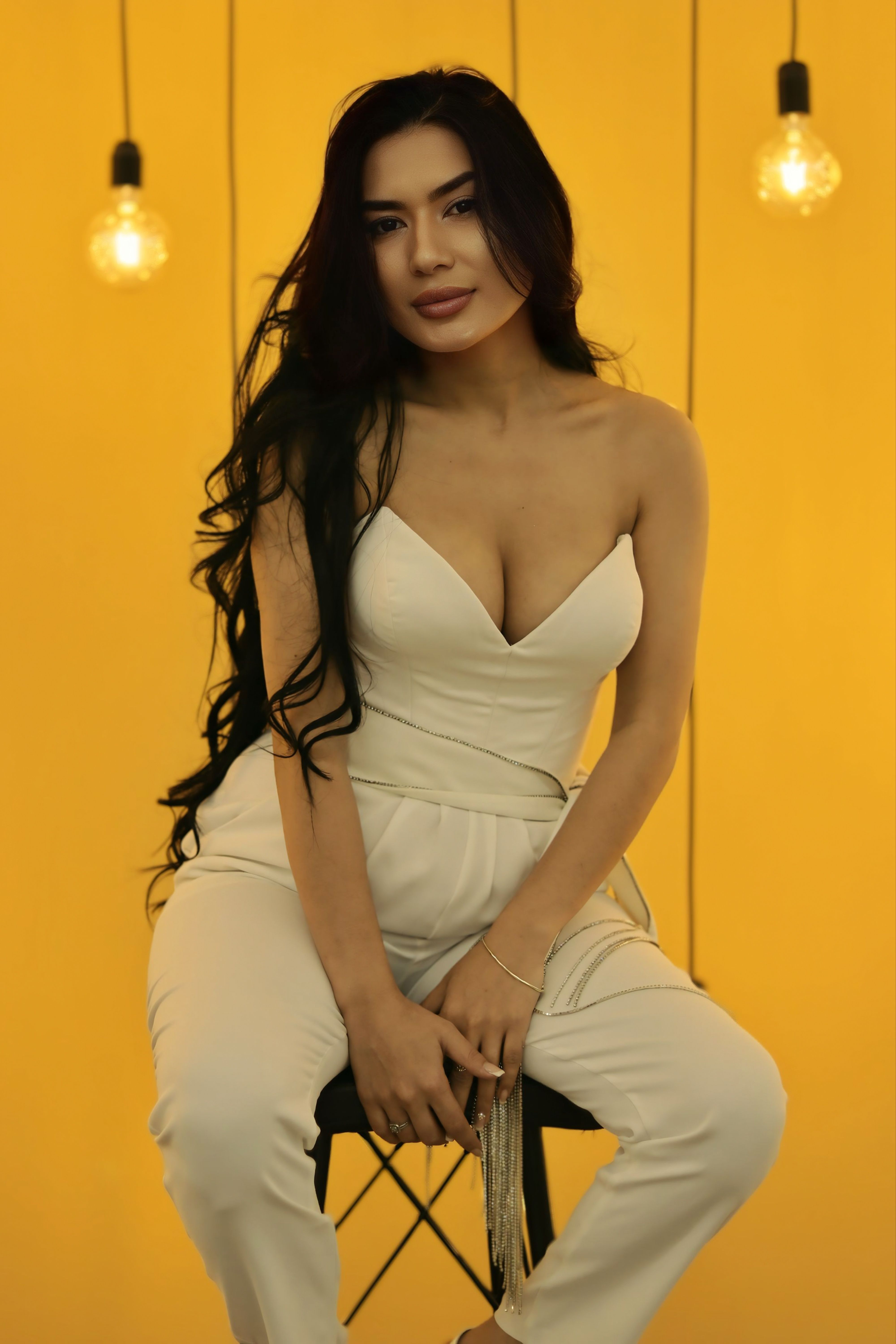 Stylish woman in white outfit with hanging lights, creating a warm, inviting atmosphere.