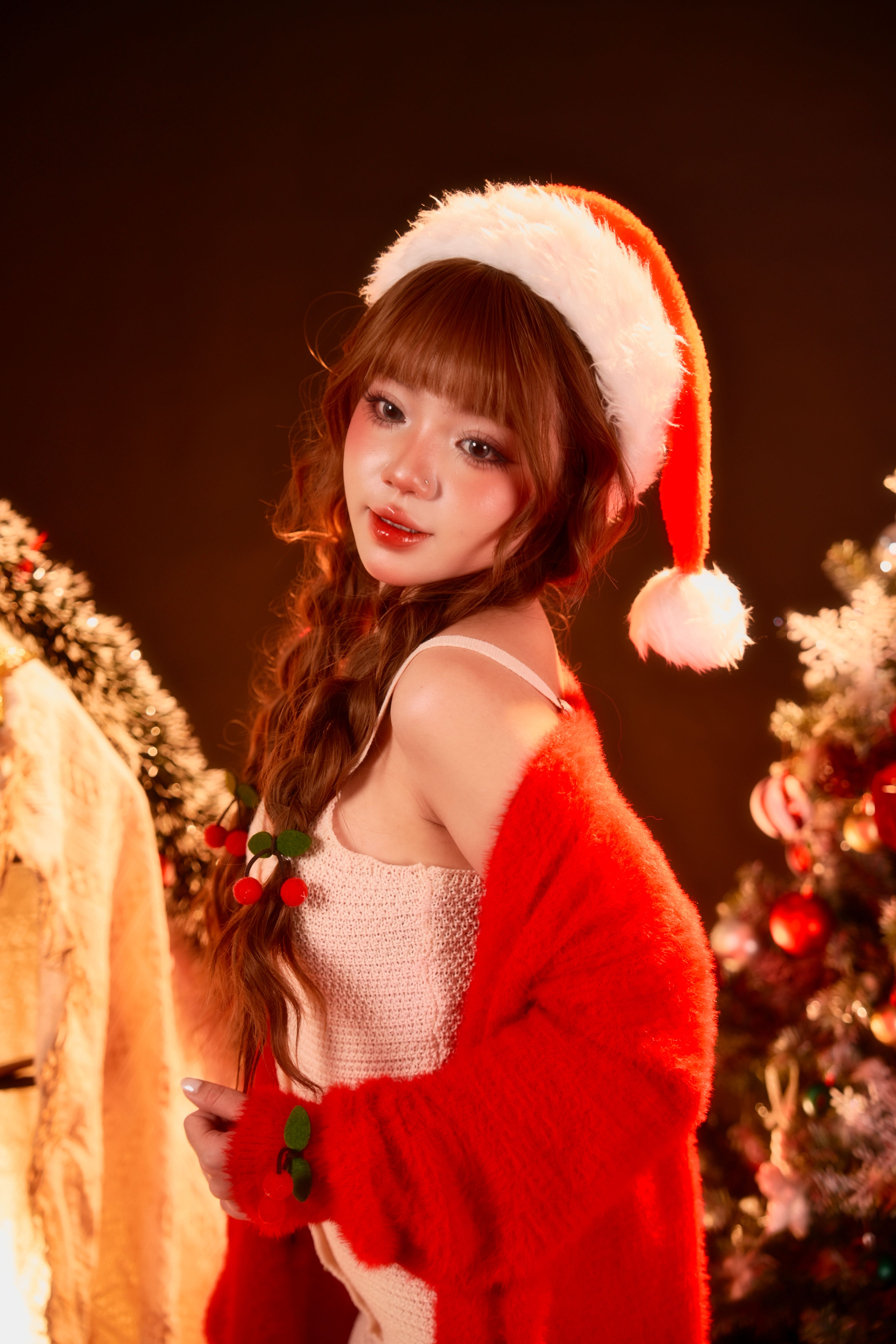 A young woman in a Santa hat celebrating Christmas indoors.