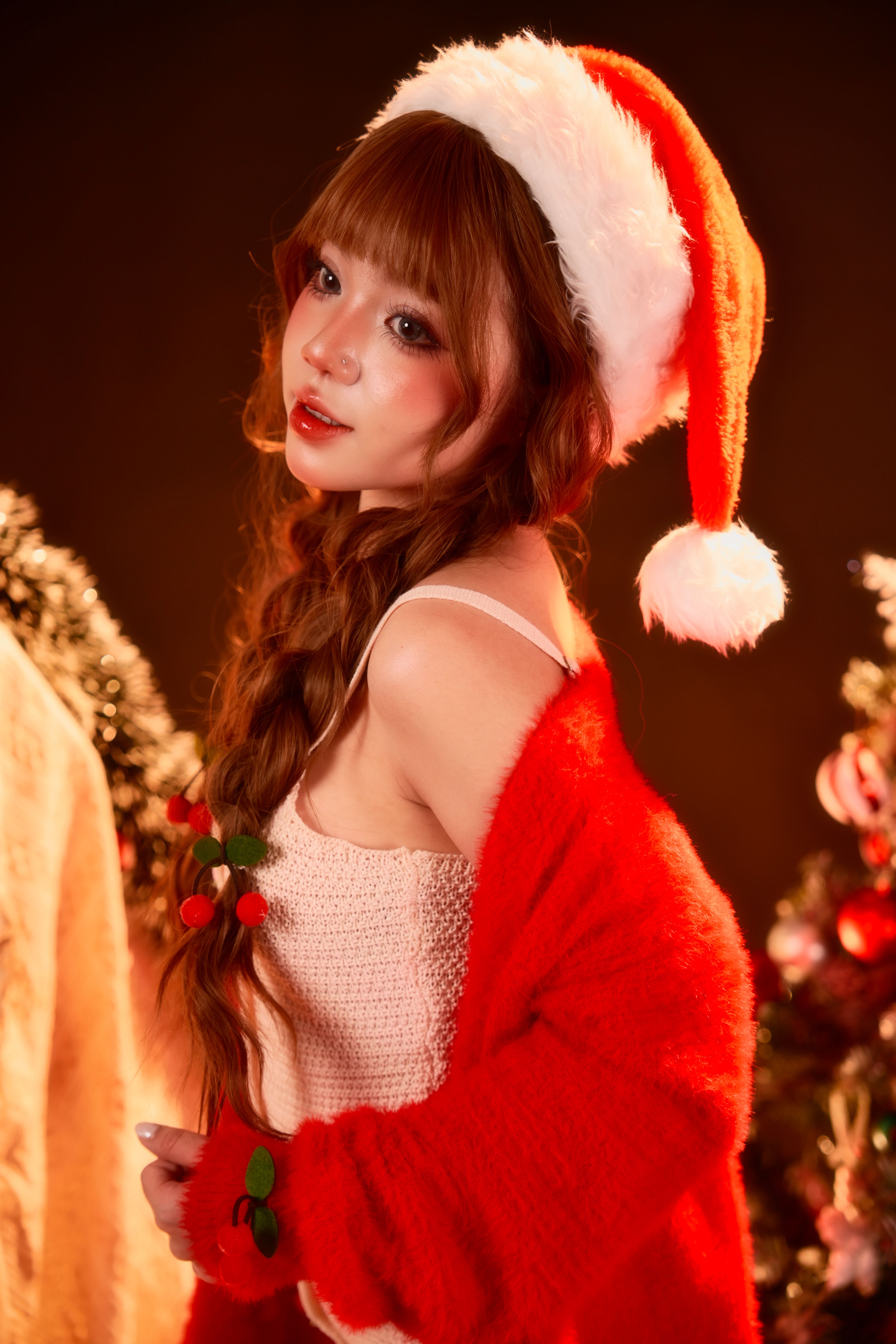 Young woman in Christmas attire posing with a Santa hat, embodying festive cheer.