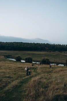 A peaceful countryside scene with a family walking on a trail during dusk.