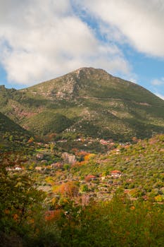 Explore a picturesque mountain village surrounded by vibrant autumn foliage in Greece.