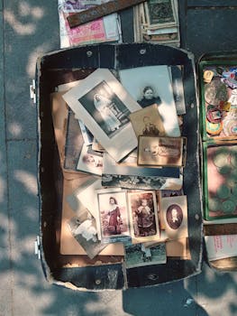 Collection of vintage photographs in an open suitcase, sunlight and shadows outdoors.