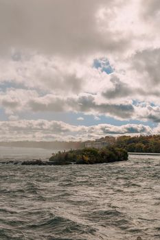Picturesque autumn landscape with island and dramatic cloudy sky over a lake.