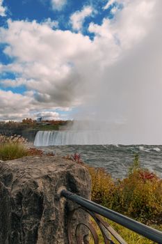 Capture the breathtaking Niagara Falls with vibrant autumn foliage and clear skies.