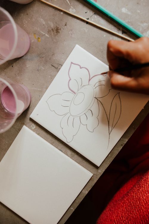 Free Hand drawing a floral design on a ceramic tile with paintbrush, artistic process captured. Stock Photo