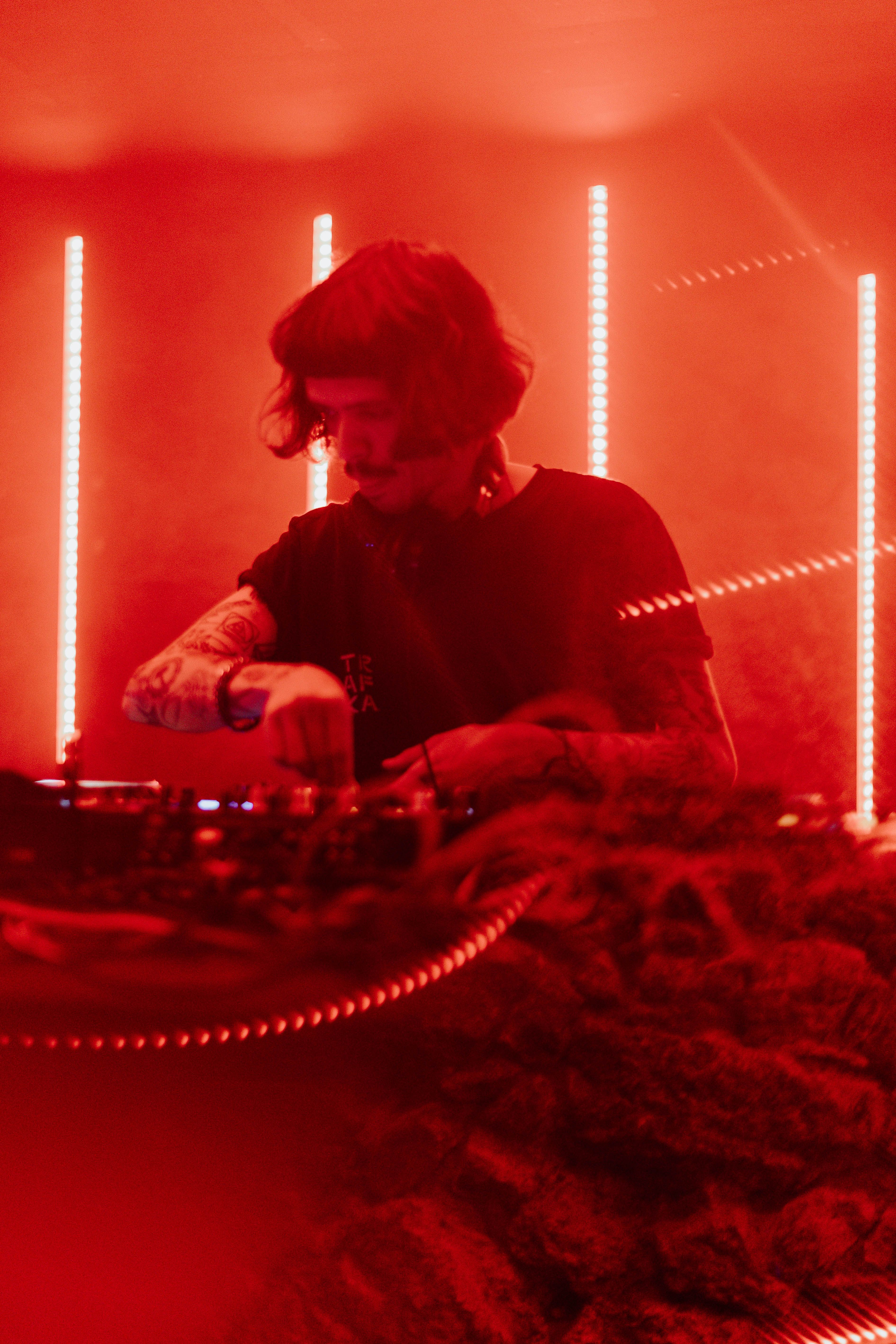 A DJ sets the mood with vibrant red lights in a club in Porto, Portugal.