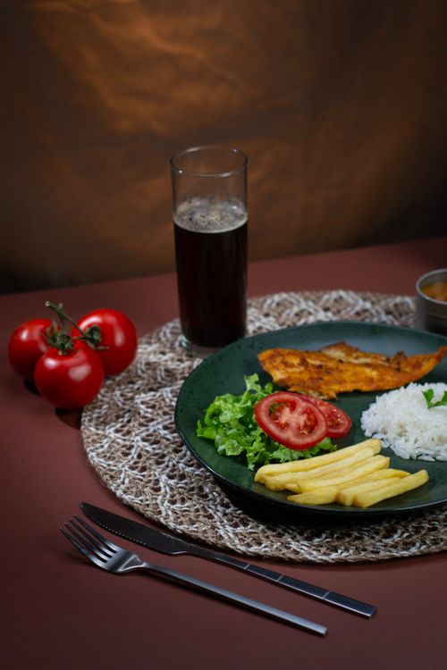Free Delicious Brazilian meal with grilled chicken, rice, salad, and french fries on a set table. Stock Photo