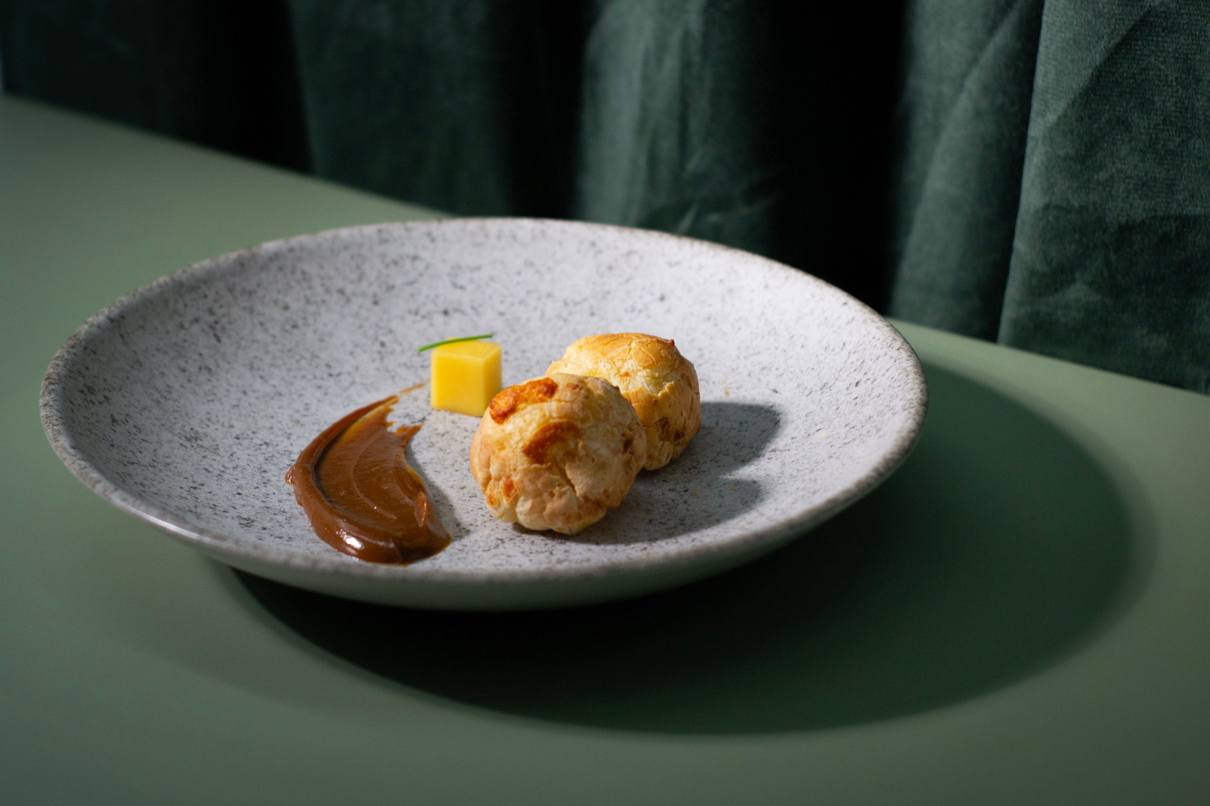 Sophisticated Brazilian cheese bread plated elegantly with chocolate sauce and mango dice.