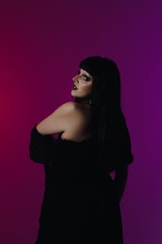 Conceptual portrait of a woman in gothic style with dark makeup against a colorful backdrop.