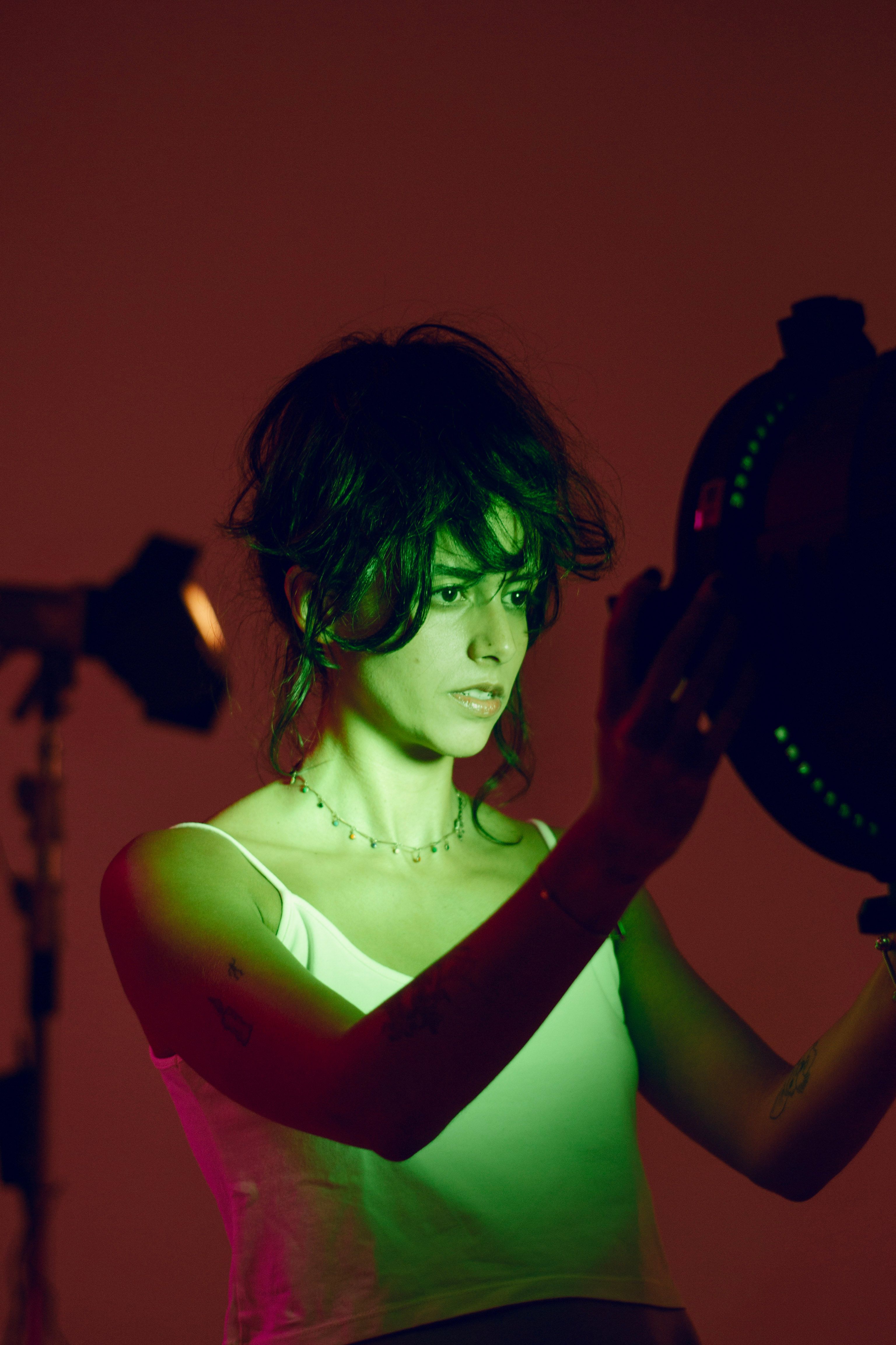 Creative portrait of a woman with vibrant green lighting in a photo studio.