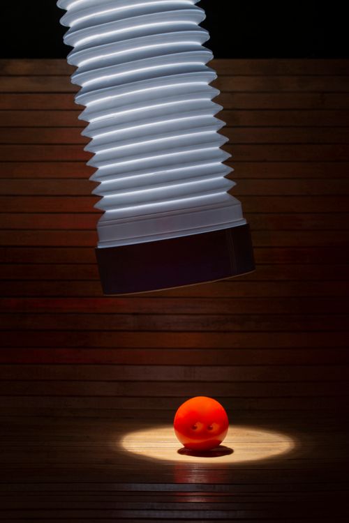 Free A vivid red ball illuminated by a large industrial light in a wooden room. Stock Photo