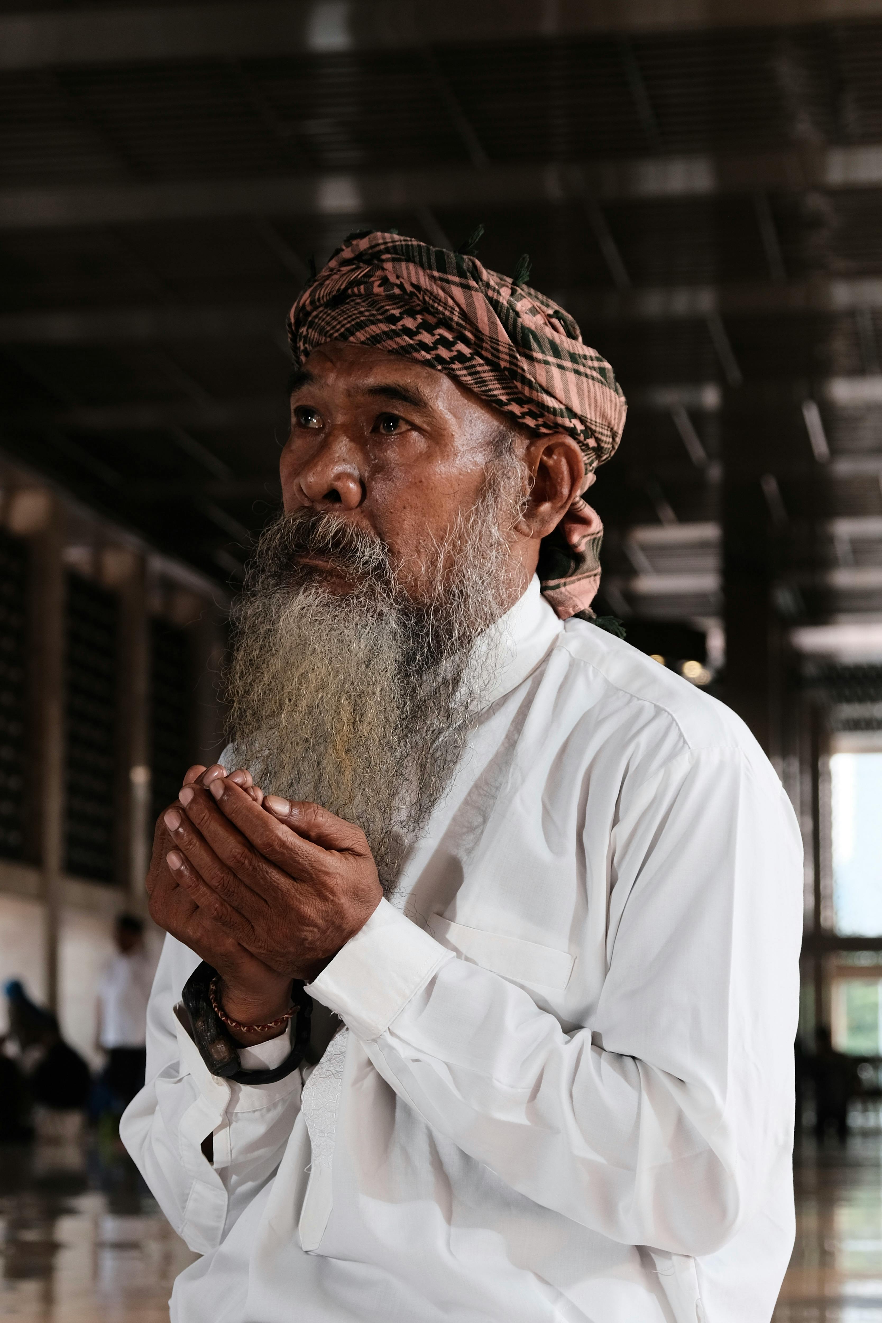 An elderly man in a mosque praying with devotion and focus.