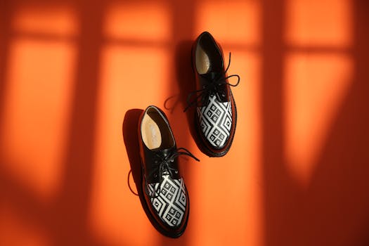 Elegant black and white patterned leather shoes on an eye-catching orange background with dramatic shadows.