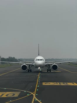 Front view of a commercial airplane taxiing on the runway at New Delhi airport under cloudy skies.