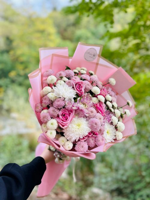 Free A beautiful bouquet of pink and white flowers held outdoors with a soft, natural background. Stock Photo