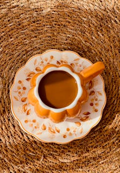 An artistic top view of a pumpkin-shaped coffee cup on a woven mat in autumn.