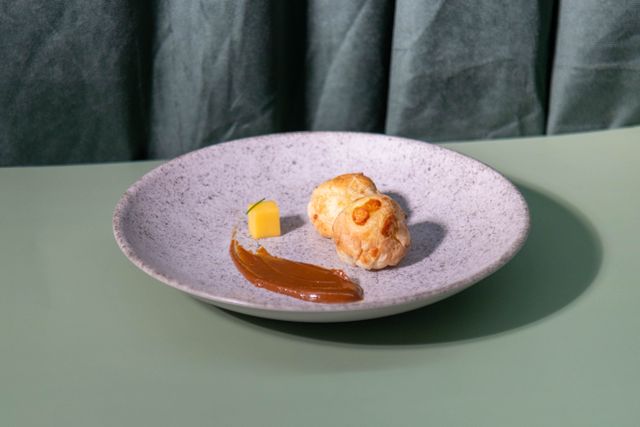 A gourmet pastry on a stylish plate with caramel spread and a cheese cube. Perfect for food photography.