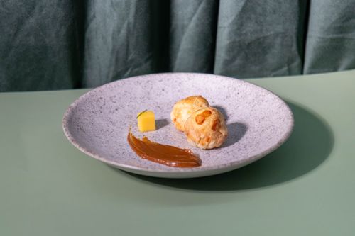 Free A gourmet pastry on a stylish plate with caramel spread and a cheese cube. Perfect for food photography. Stock Photo