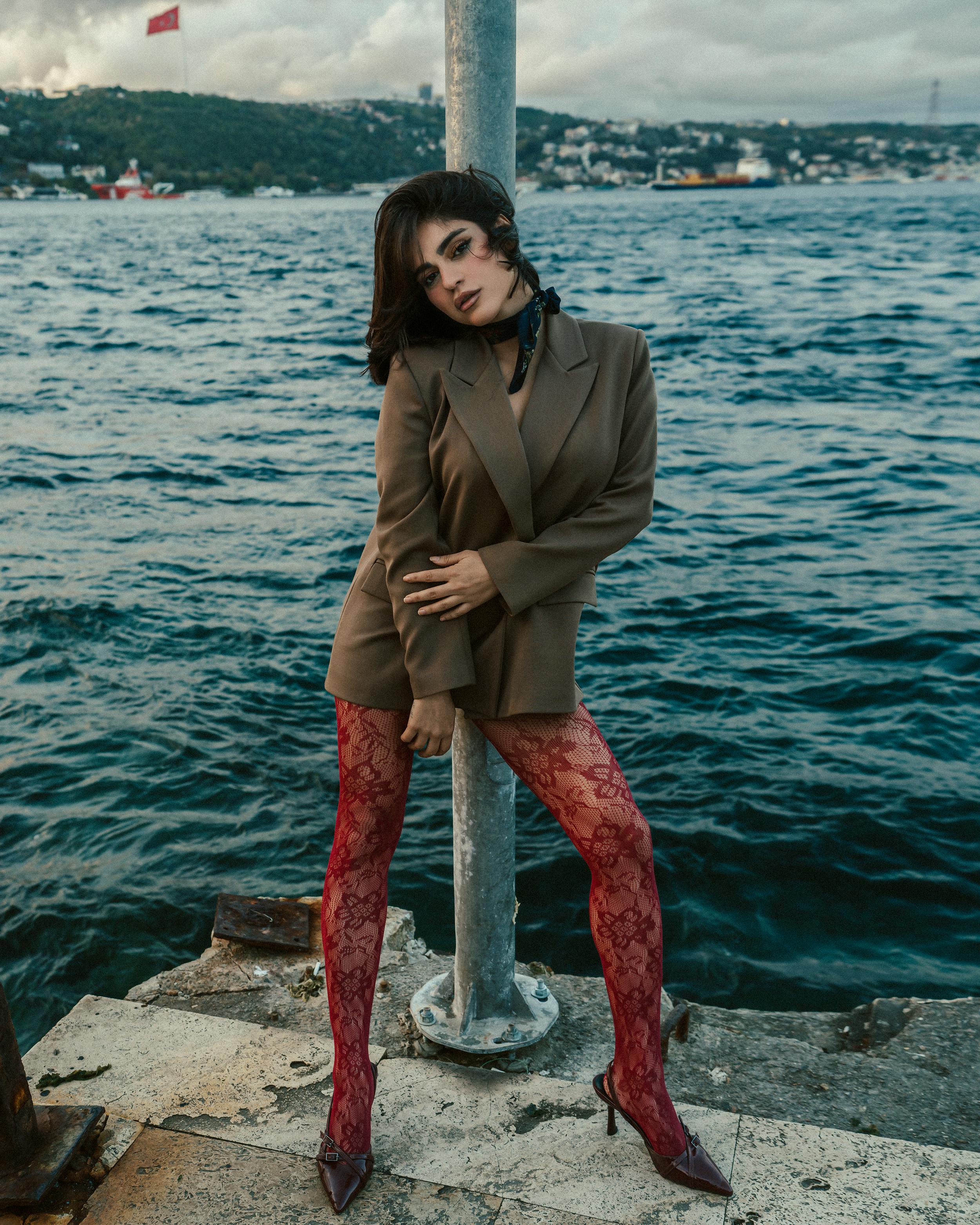 Stylish woman in red lace tights posing by the scenic Bosphorus waterfront.