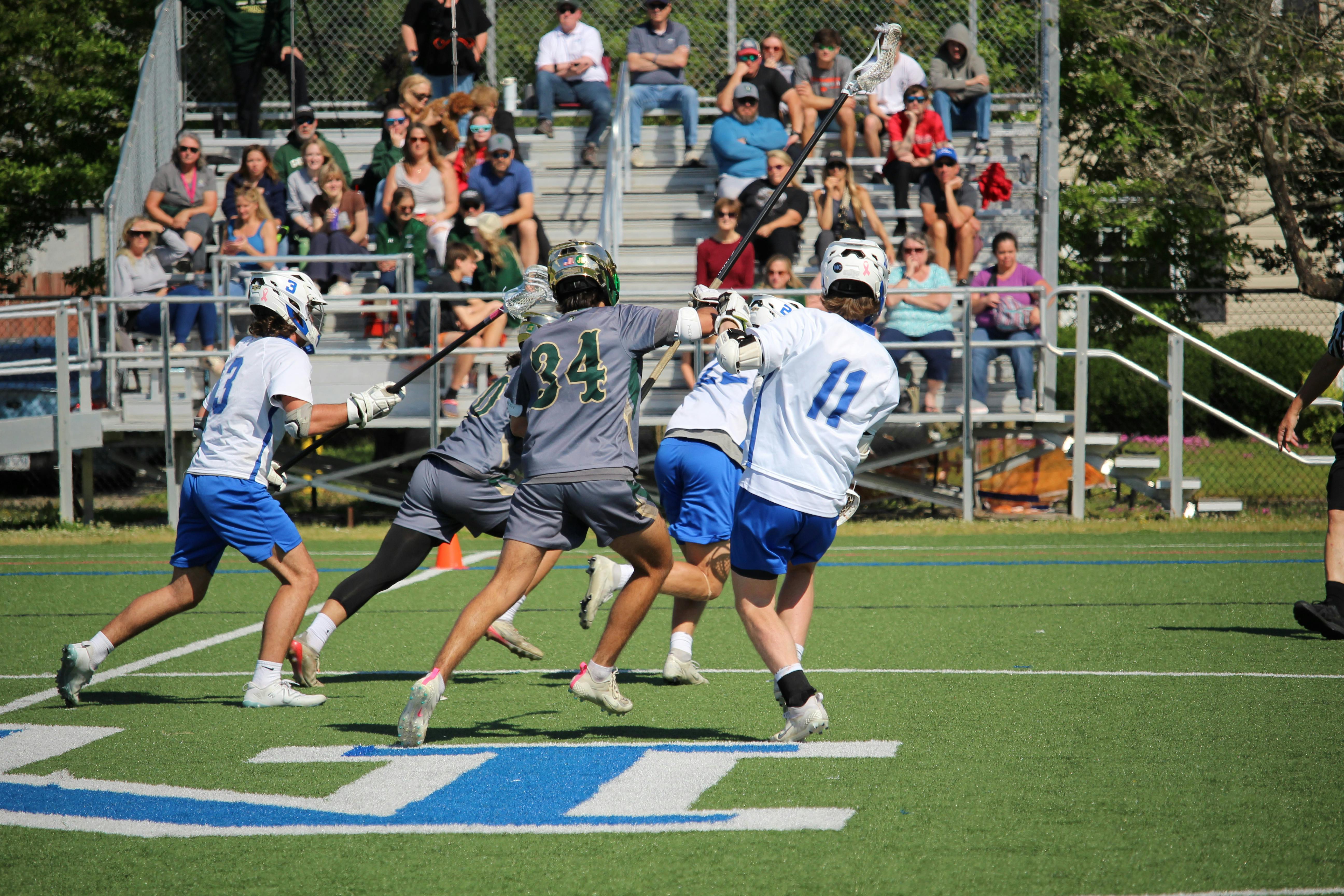 De franc Un partit competitiu de lacrosse de secundària amb jugadors en moviment en un dia assolellat. Foto d'estoc