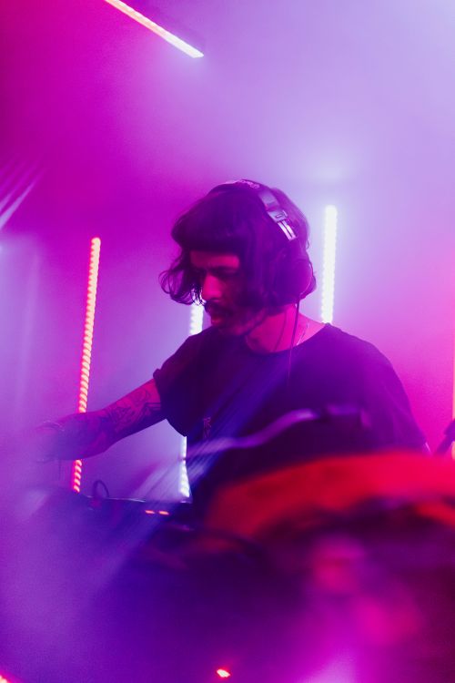 Free A DJ mixing tracks in a vibrant nightclub setting with colorful lights. Stock Photo